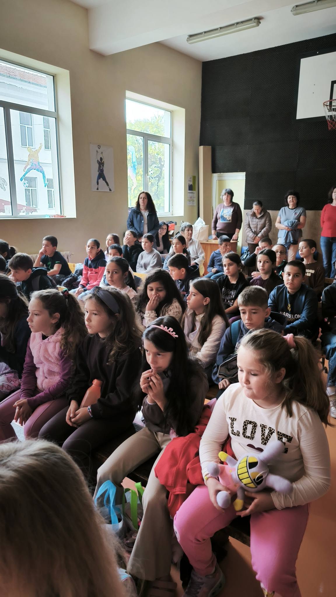Ученици от начален етап слушат презентация в училищната зала.