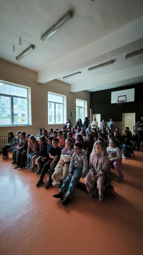 Ученици са подредени в две групи пред екрана.